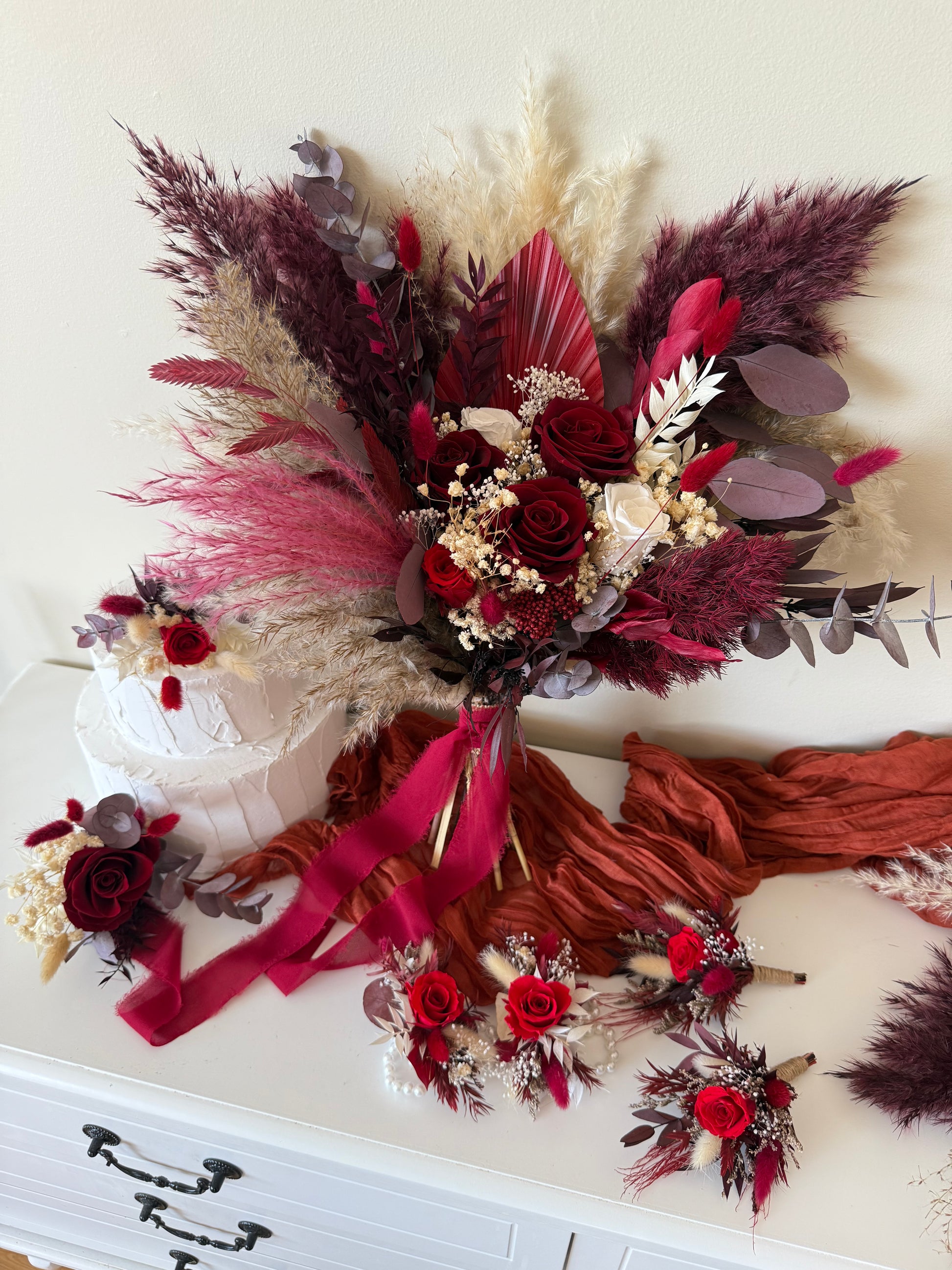 One-sided bridal bouquet in burgundy and ivory tones with pampas grass and sola wood roses, perfect for boho rustic weddings