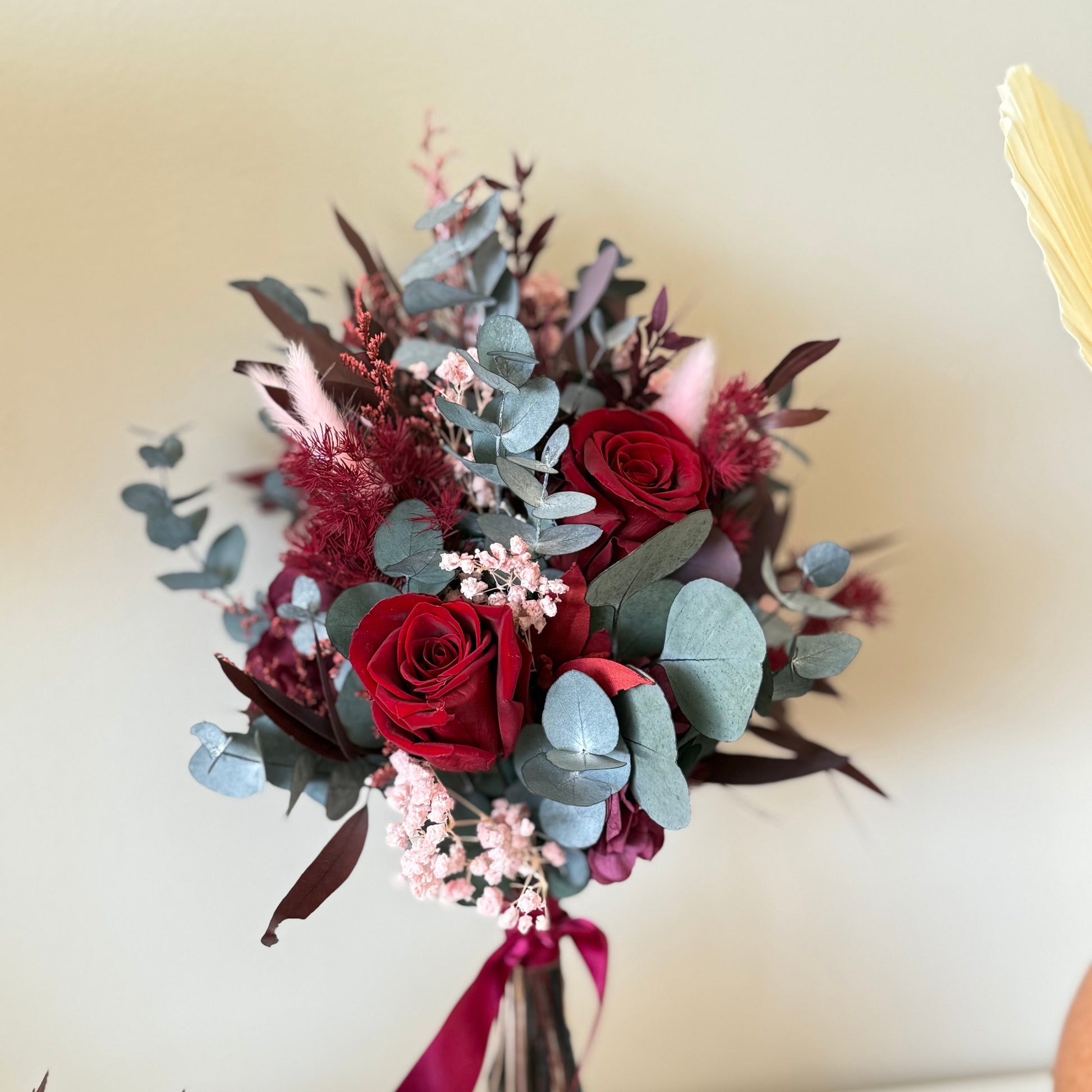 Burgundy dried flower wedding bouquet tied with ribbon, elegant bridal florals