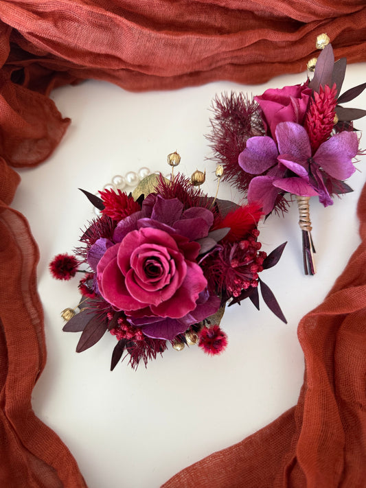Elegant burgundy wrist corsage on pearl bracelet with matching boutonniere for prom or wedding
