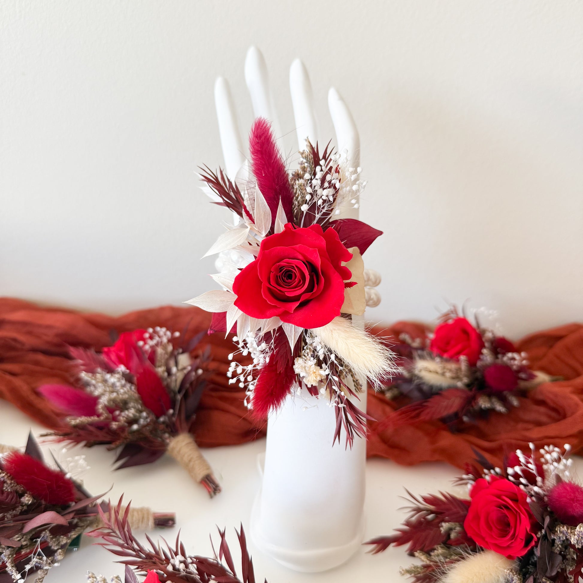Decorative floral arrangement with red roses and candles in a white vase on a white background.