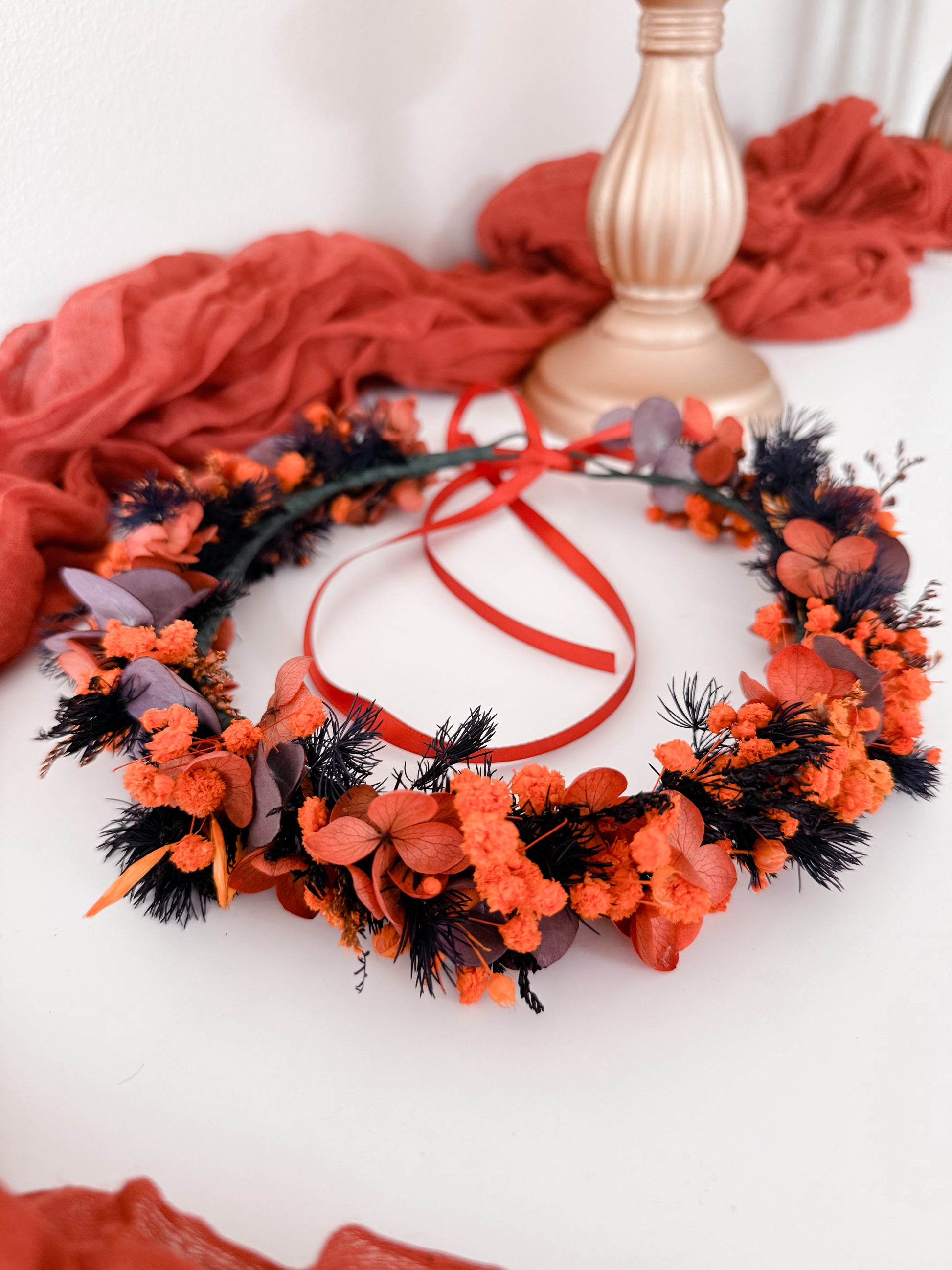Top view of burnt orange and plum dried floral wreath with fluffy grass and hydrangea.