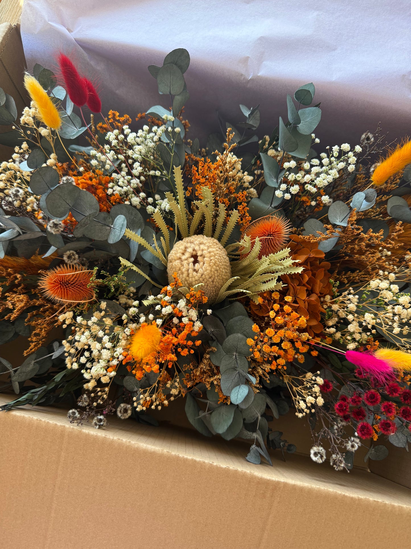 Bouquet of dried flowers and greenery in a cardboard box