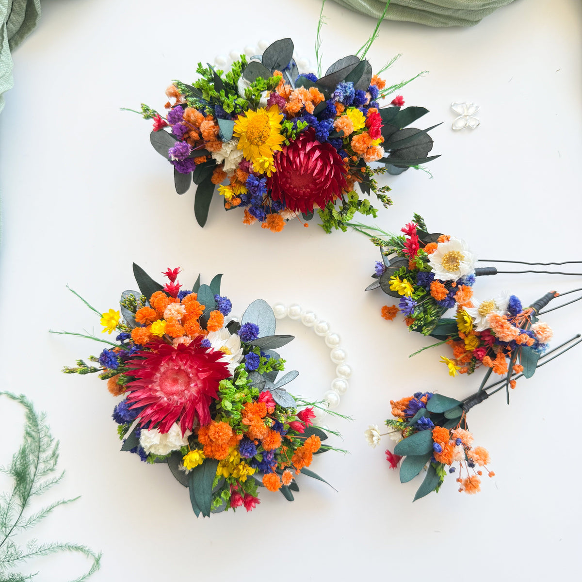 Colourful preserved flower wrist corsages and hair pins with orange, blue, yellow and red dried flowers for weddings and formals
