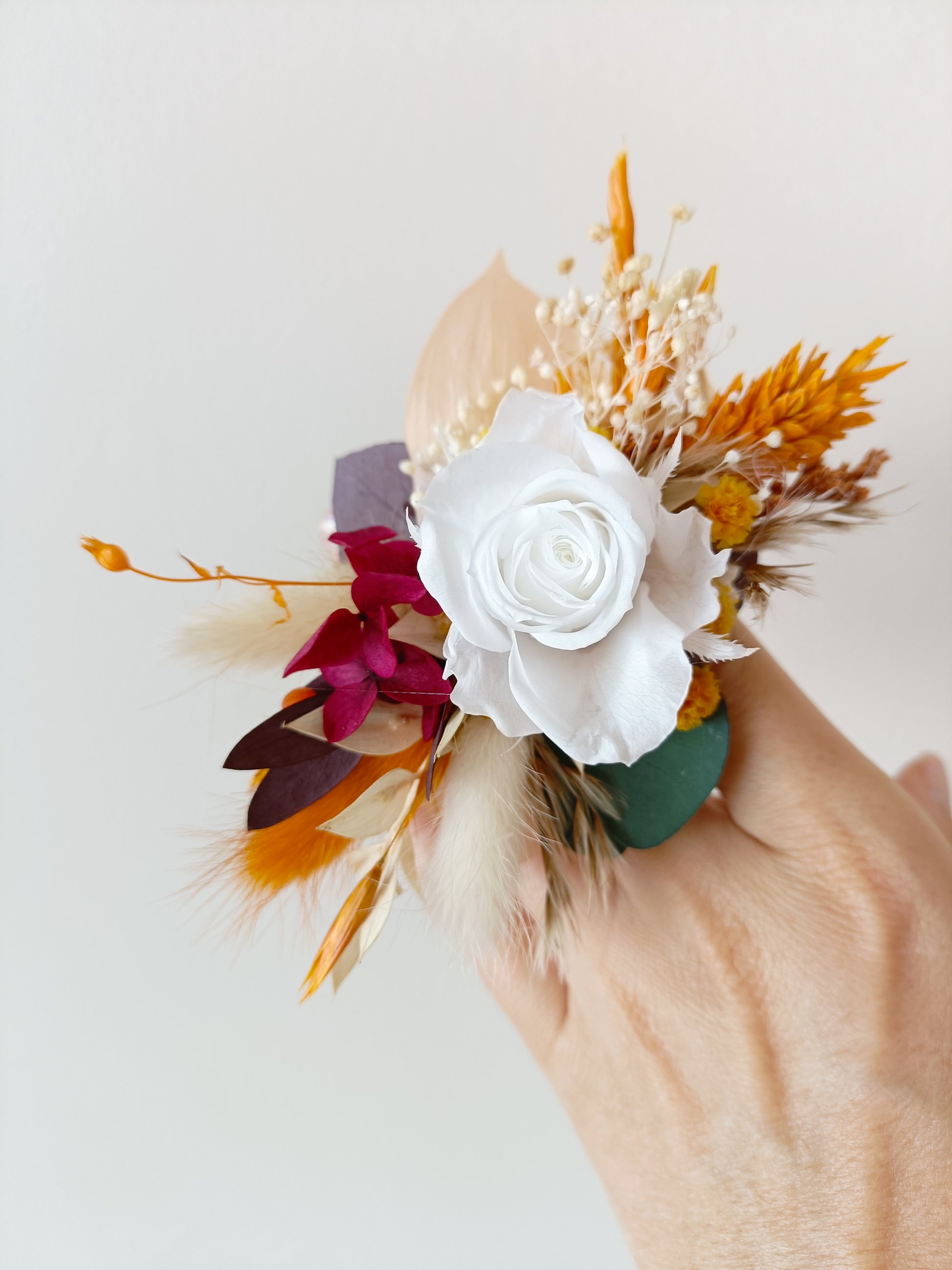 Handmade floral corsage for wedding featuring dried leaves, white flower and gold tones