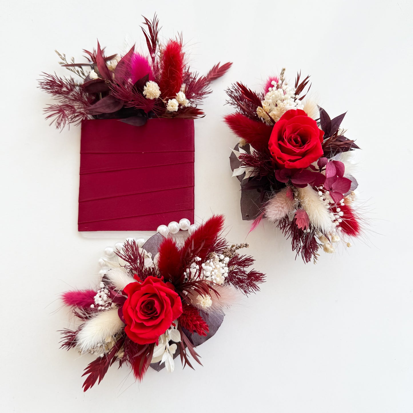 Elegant crimson dried flower wrist corsage featuring preserved roses, white accents and natural textures, ideal for weddings, birthdays or home styling.