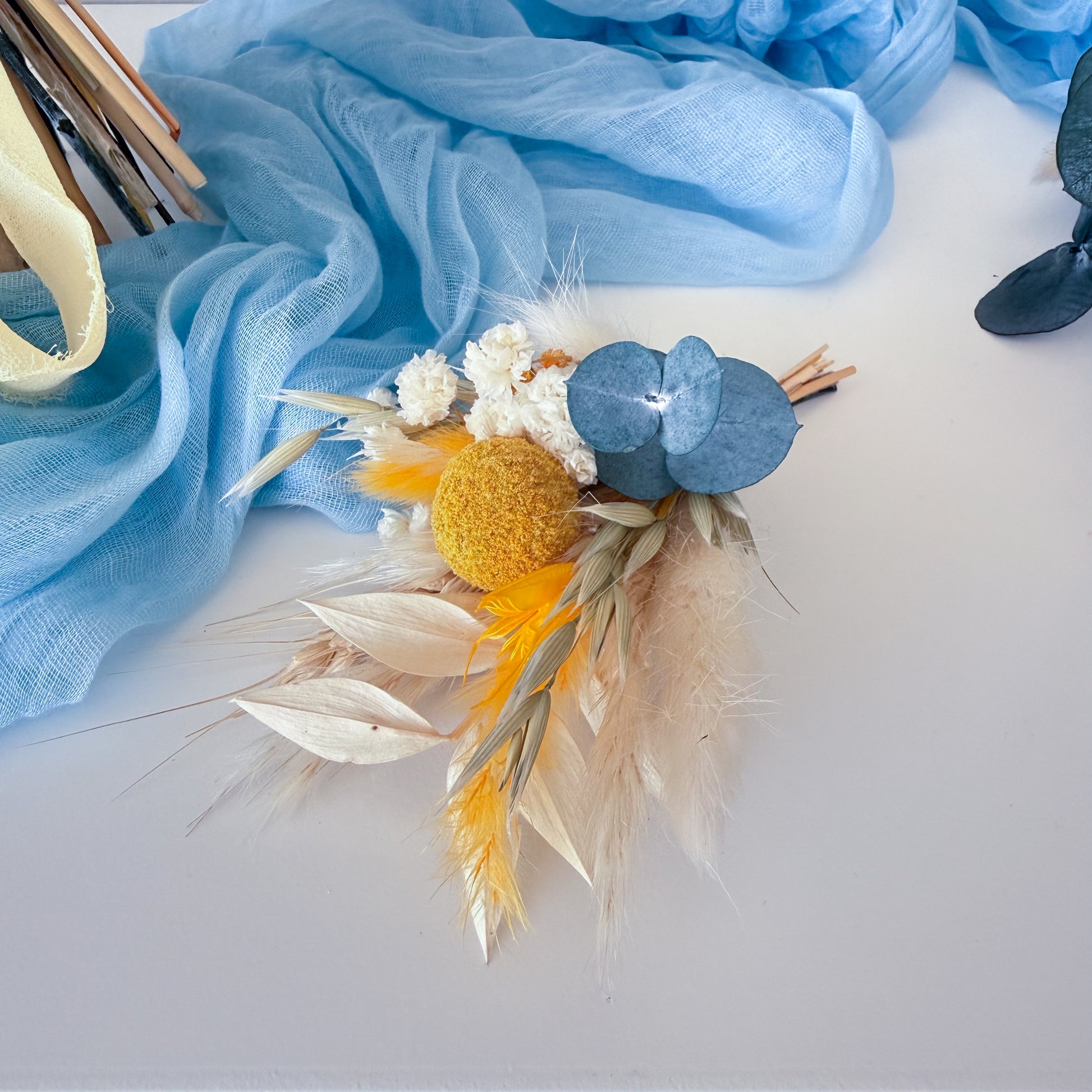 Close-up of boho wedding boutonniere with dried flowers, yellow accents and blue eucalyptus