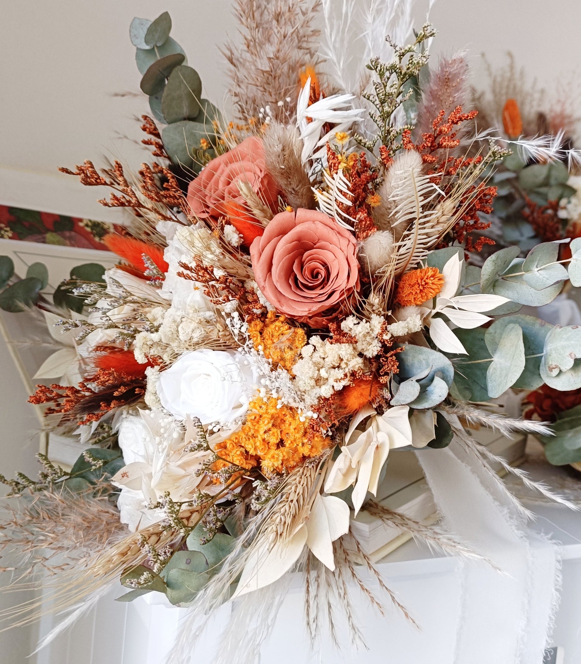 Stunning wedding bouquet made of dried flowers, featuring rustic hues of orange, beige, and green. This handcrafted arrangement includes preserved roses, eucalyptus, pampas grass, and other textural elements, perfect for a boho-chic wedding. Available for custom orders