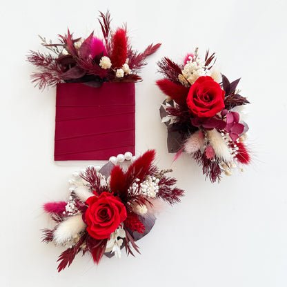 Three floral accessories with red roses and dried foliage on a white background