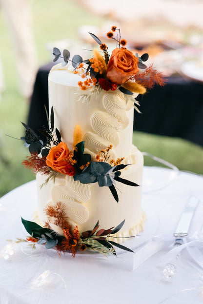 Natural dried and preserved cake topper arrangement featuring terracotta roses, warm orange blooms and dried foliage for a romantic boho wedding.
