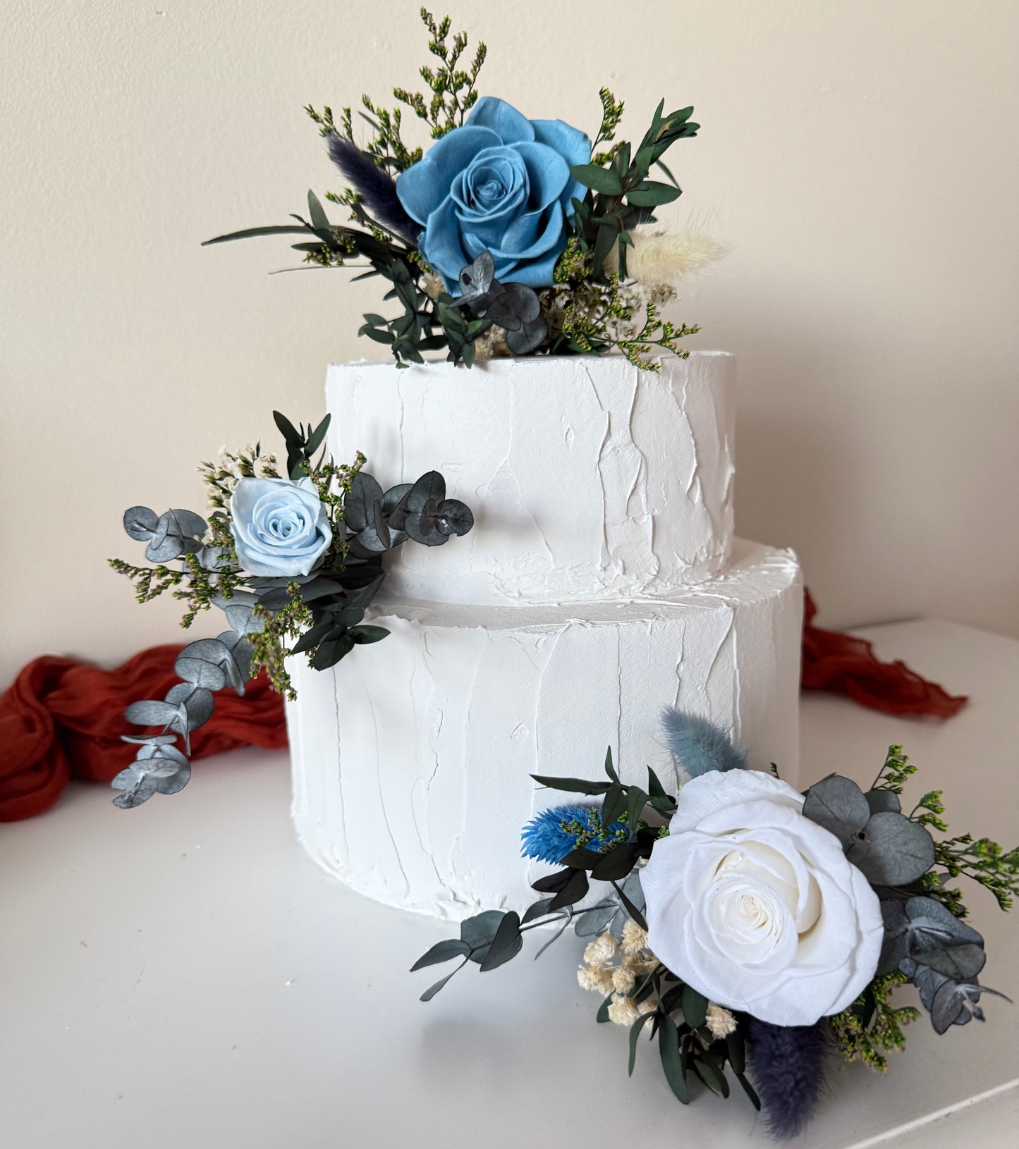 Dried flower cake decoration with blue and ivory preserved roses, perfect for matching boho wedding bouquets.
