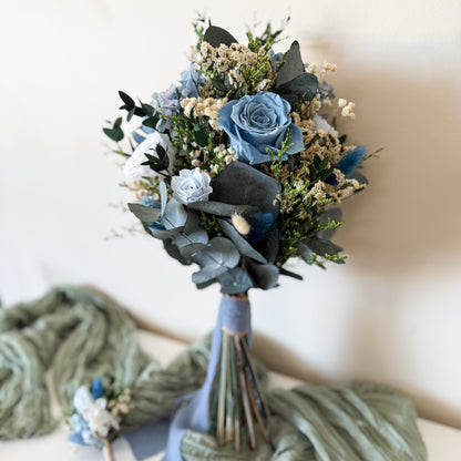 Handmade wedding bouquet in dusty blue and ivory tones with preserved greenery and sola wood flowers, ideal for brides.