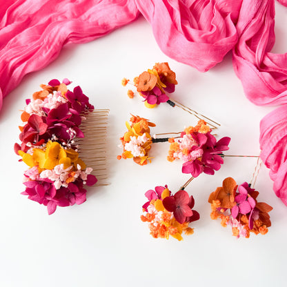 Colorful floral hair accessories on a white surface with pink fabric.