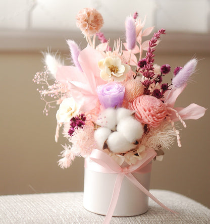 Pink and purple dried flower arrangement in a round white box with cotton, sola flowers, and preserved florals. Ideal for birthday gift, office decor, or thank you present.

