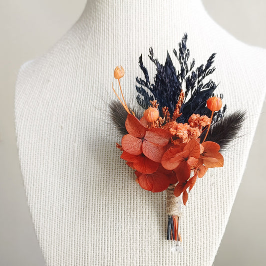 Burnt orange and navy dried flower boutonniere with preserved hydrangea and natural textures

