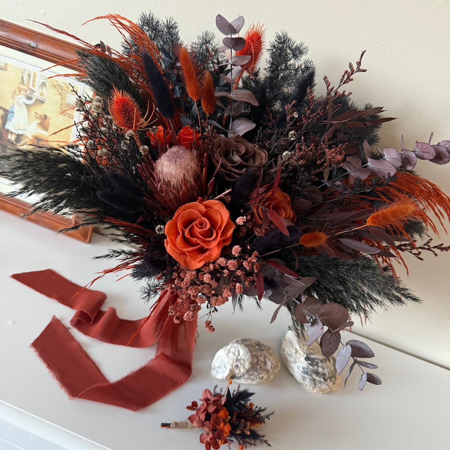 Autumnal floral arrangement with orange and brown tones on a white surface