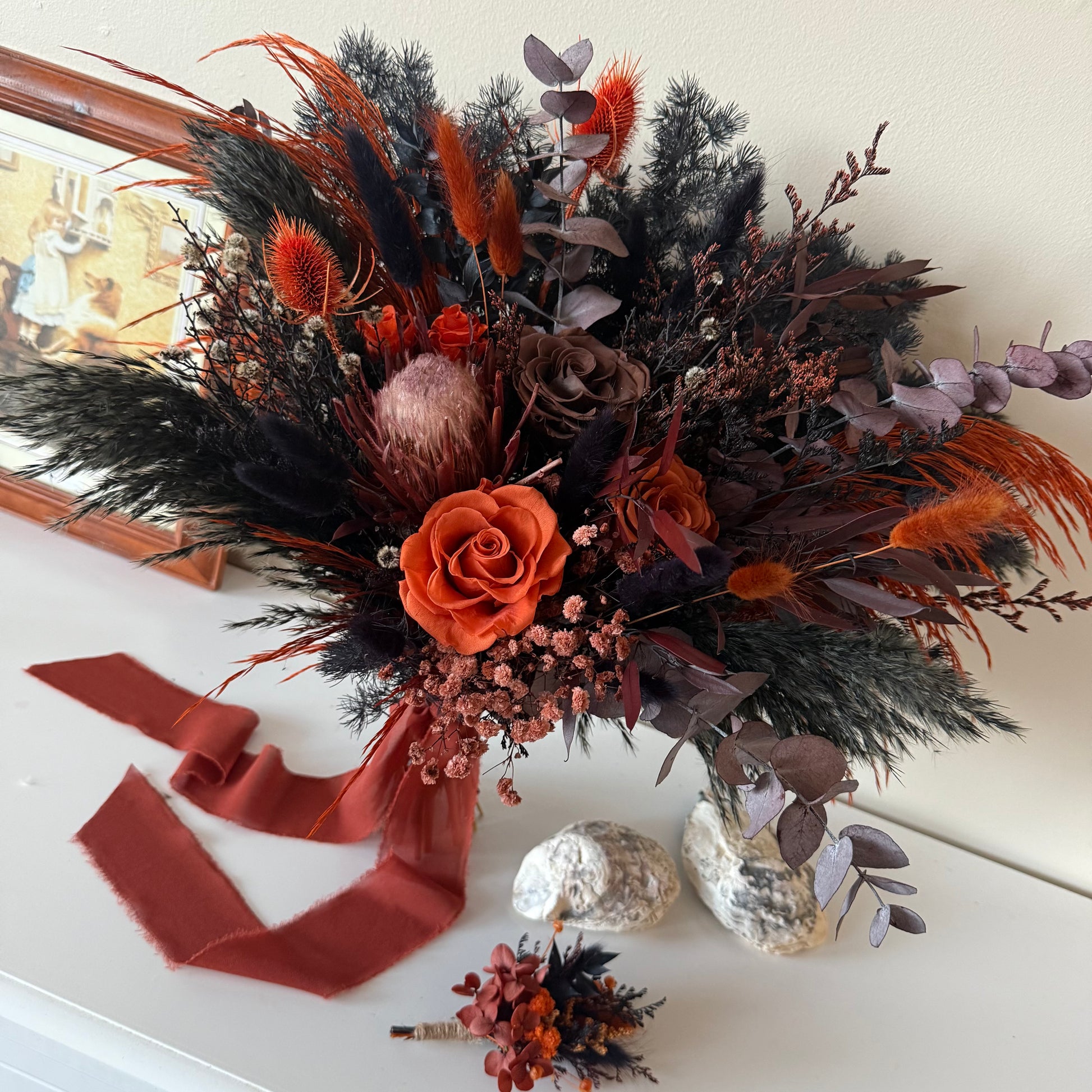 Autumnal floral arrangement with orange and brown tones on a white surface