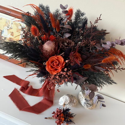 Autumnal floral arrangement with orange and brown tones on a white surface