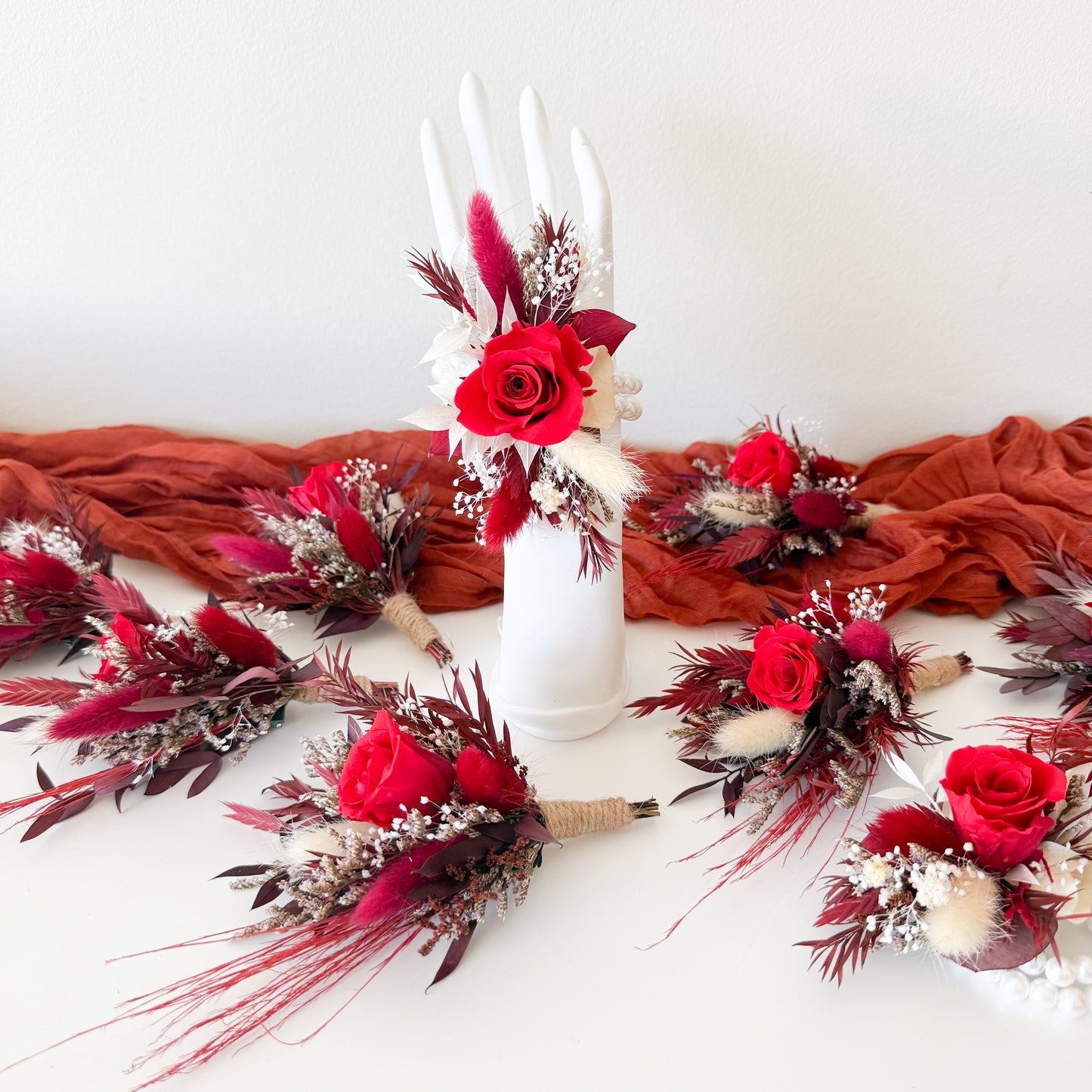 Decorative floral arrangements with red flowers and brown leaves on a white surface.