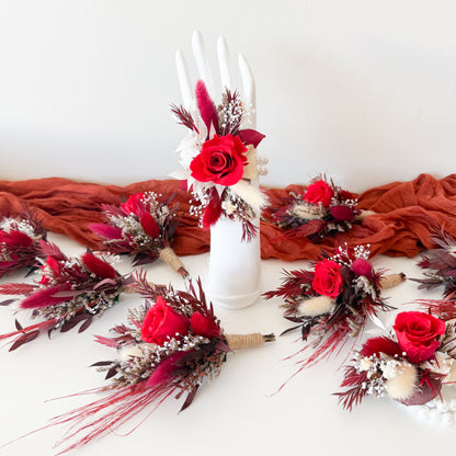 Decorative floral arrangements with red flowers and brown leaves on a white surface.
