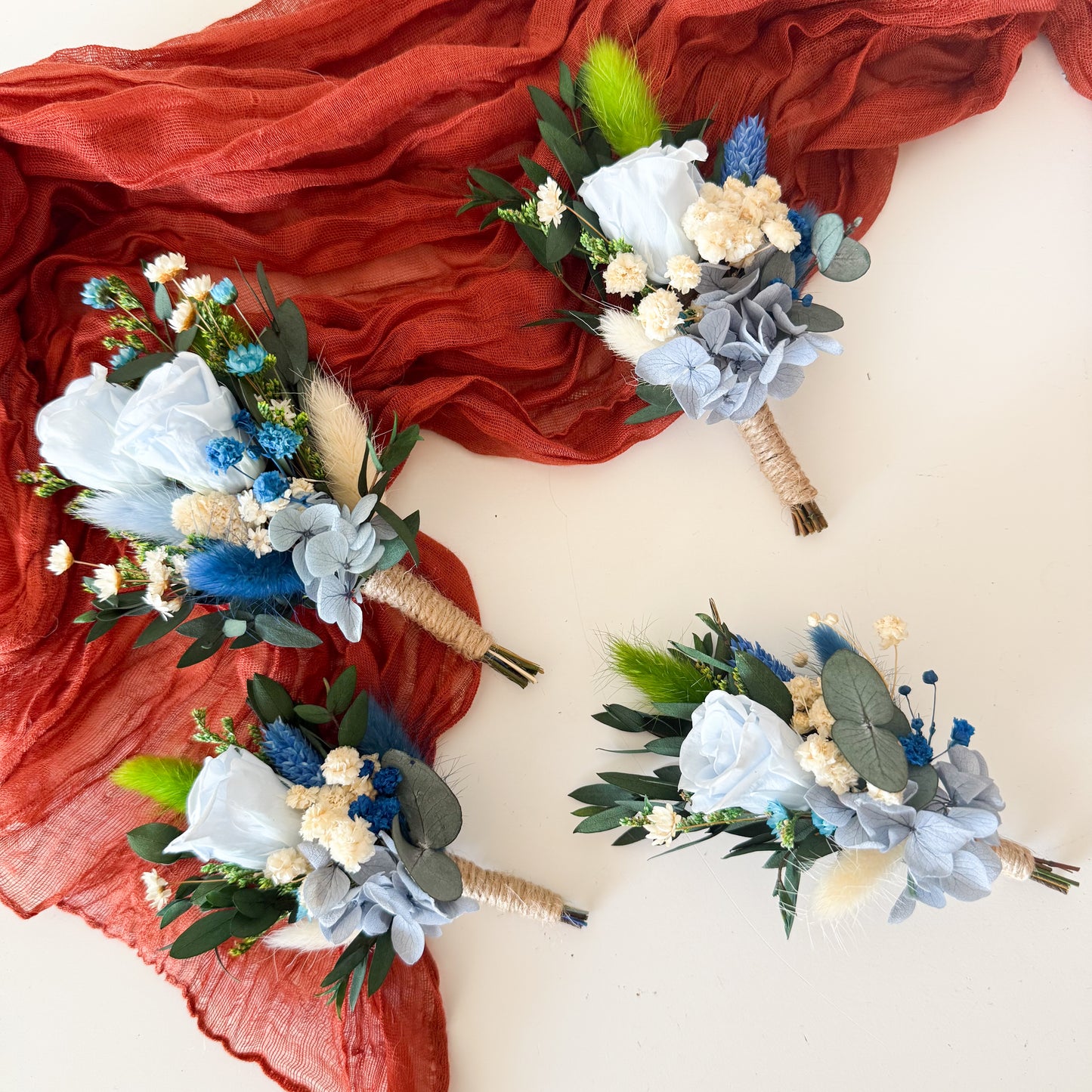 Set of wedding boutonnieres in dusty blue, white, and greenery with rustic dried flowers — matching accessories for groom and groomsmen.