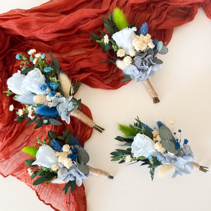 Set of wedding boutonnieres in dusty blue, white, and greenery with rustic dried flowers — matching accessories for groom and groomsmen.