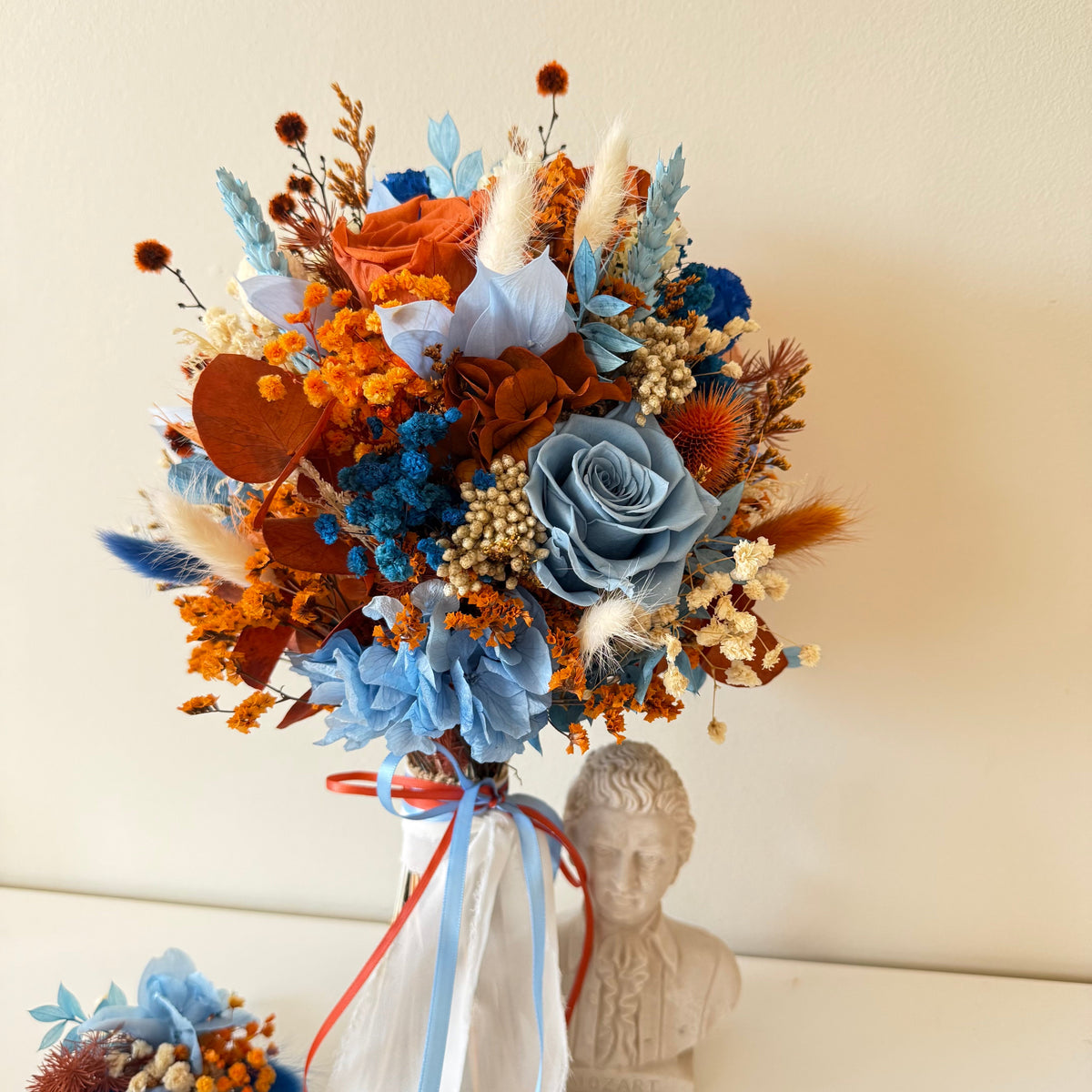 Dusty blue and burnt orange dried flower bridal bouquet with preserved roses, hydrangea and textured flowers
