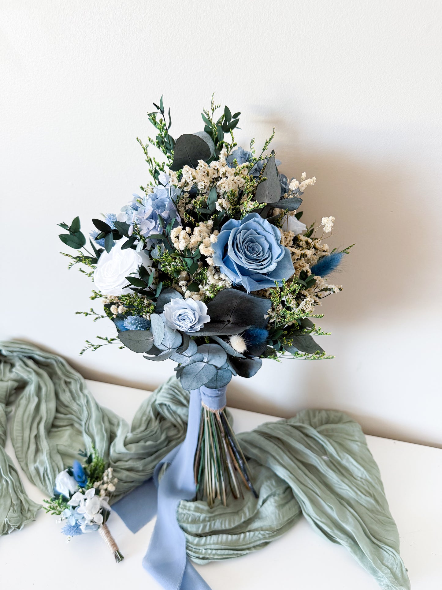dusty blue rustic bouquet with roses, eucalyptus, and preserved accents, perfect for outdoor or boho weddings.