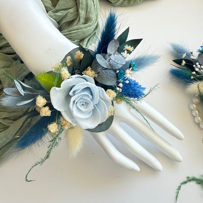 Wedding corsage in dusty blue and ivory dried flowers, including boutonniere and hairpiece.