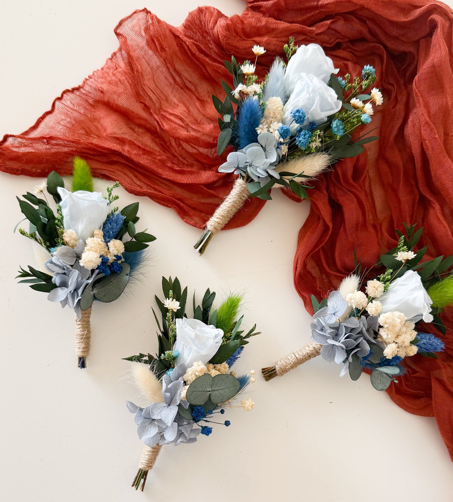 Groom boutonniere featuring dusty blue sola wood flower, preserved greenery, and dried accents — elegant boho accessory for wedding suit.