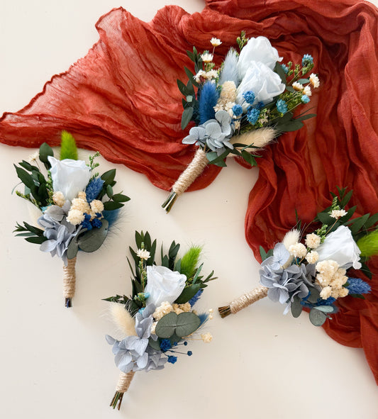 Groom boutonniere featuring dusty blue sola wood flower, preserved greenery, and dried accents â€” elegant boho accessory for wedding suit.