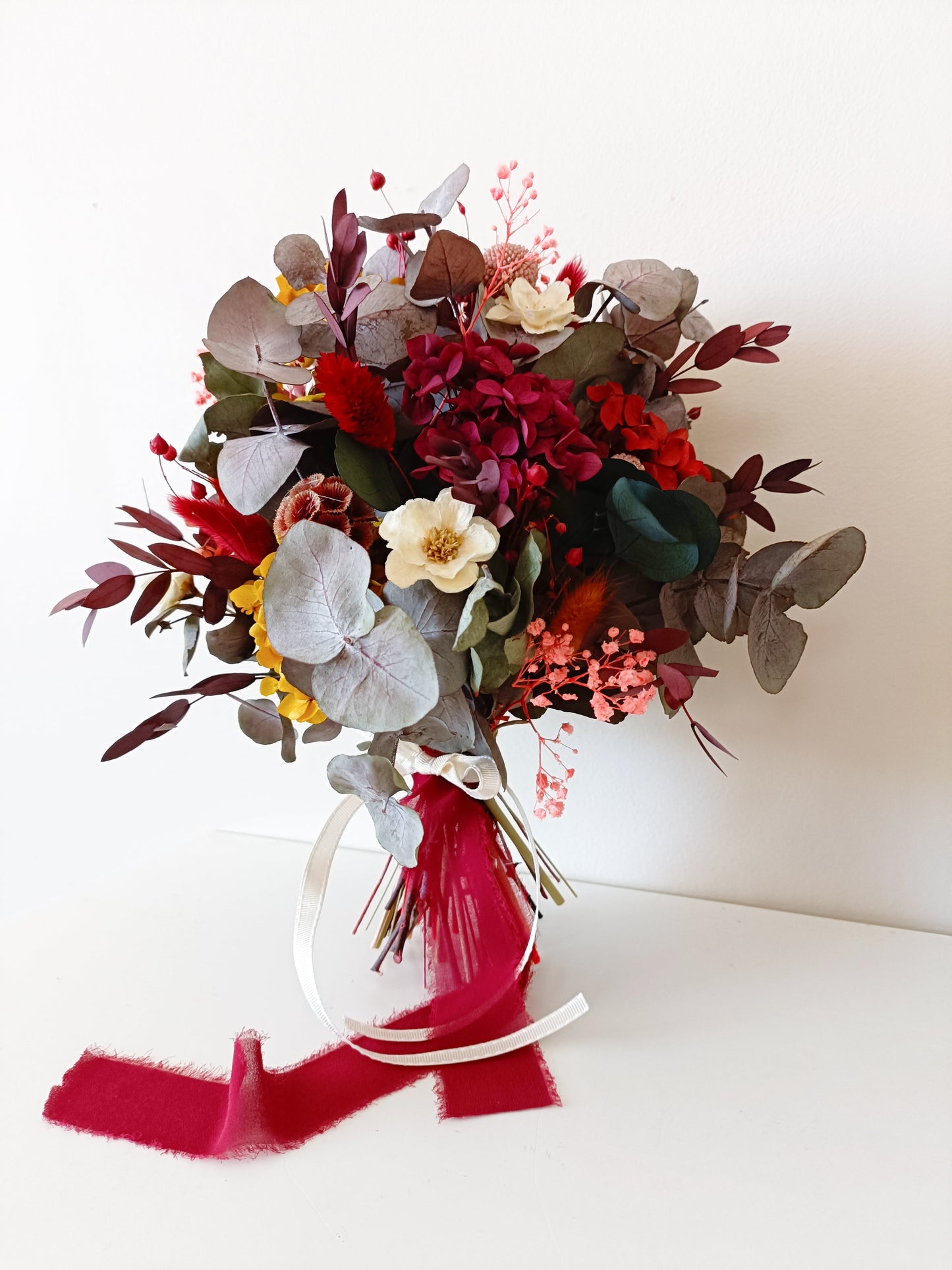 Dried flower rustic bouquet in burgundy, blush and mustard tones with preserved roses, sola flowers and eucalyptus, styled with velvet ribbon