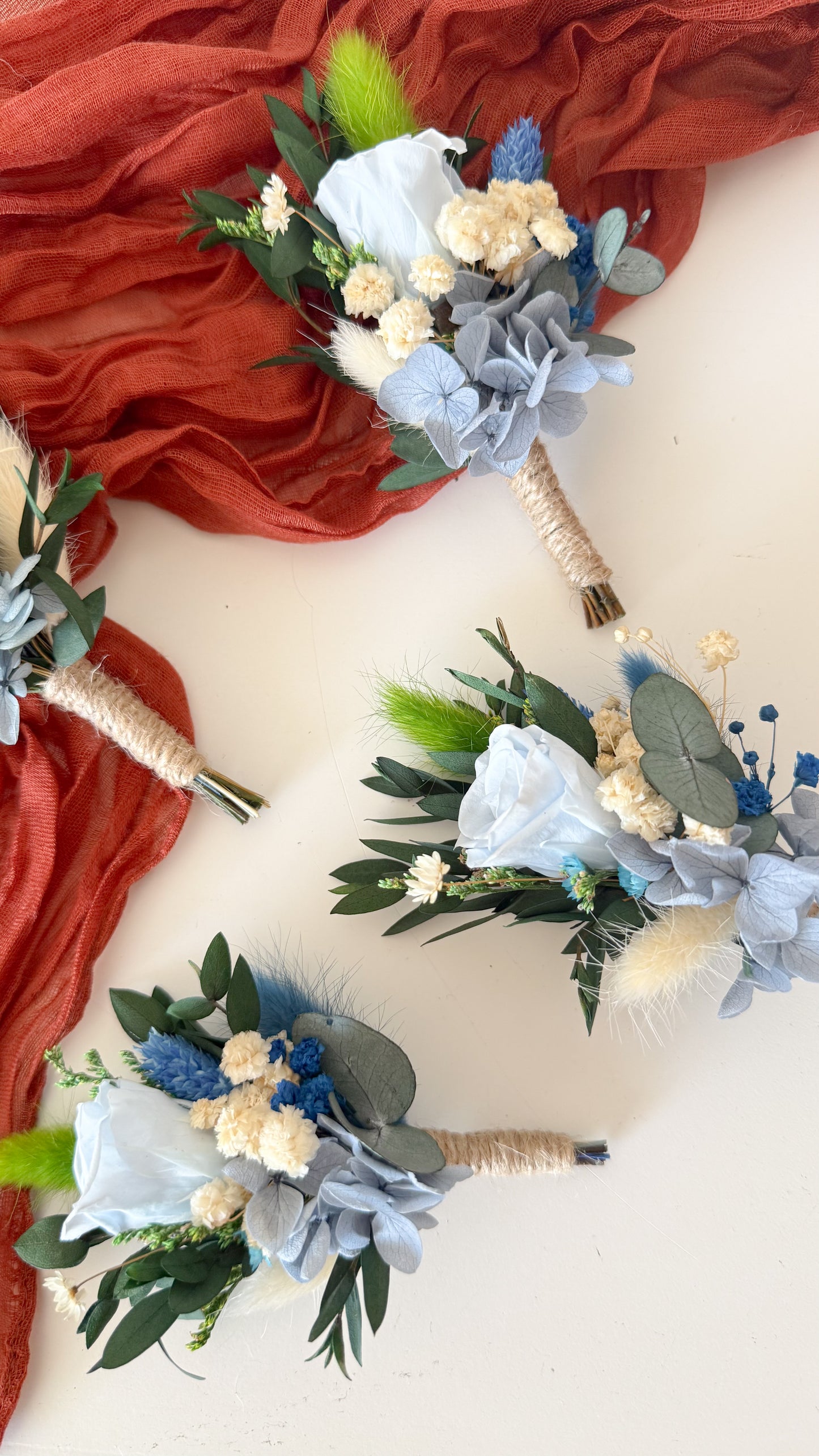 Set of floral boutonnieres on a white background with red fabric.
