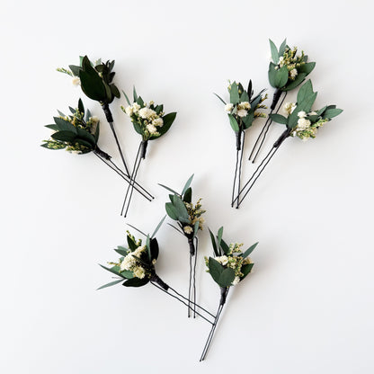 Set of three handmade bridal hair pins with preserved eucalyptus leaves and small white dried flowers.
