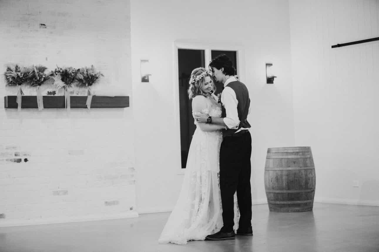 Black and white photo of a couple sharing their first dance during an indoor Australian wedding celebration