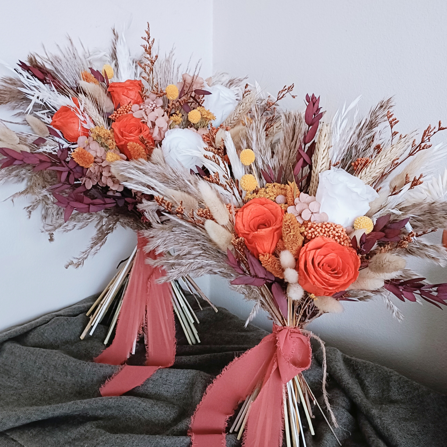 Wide dried bridal bouquet laid out on olive green fabric, showcasing preserved flowers in warm earthy tones â€“ orange, cream, plum, and beige with natural movement and boho style.