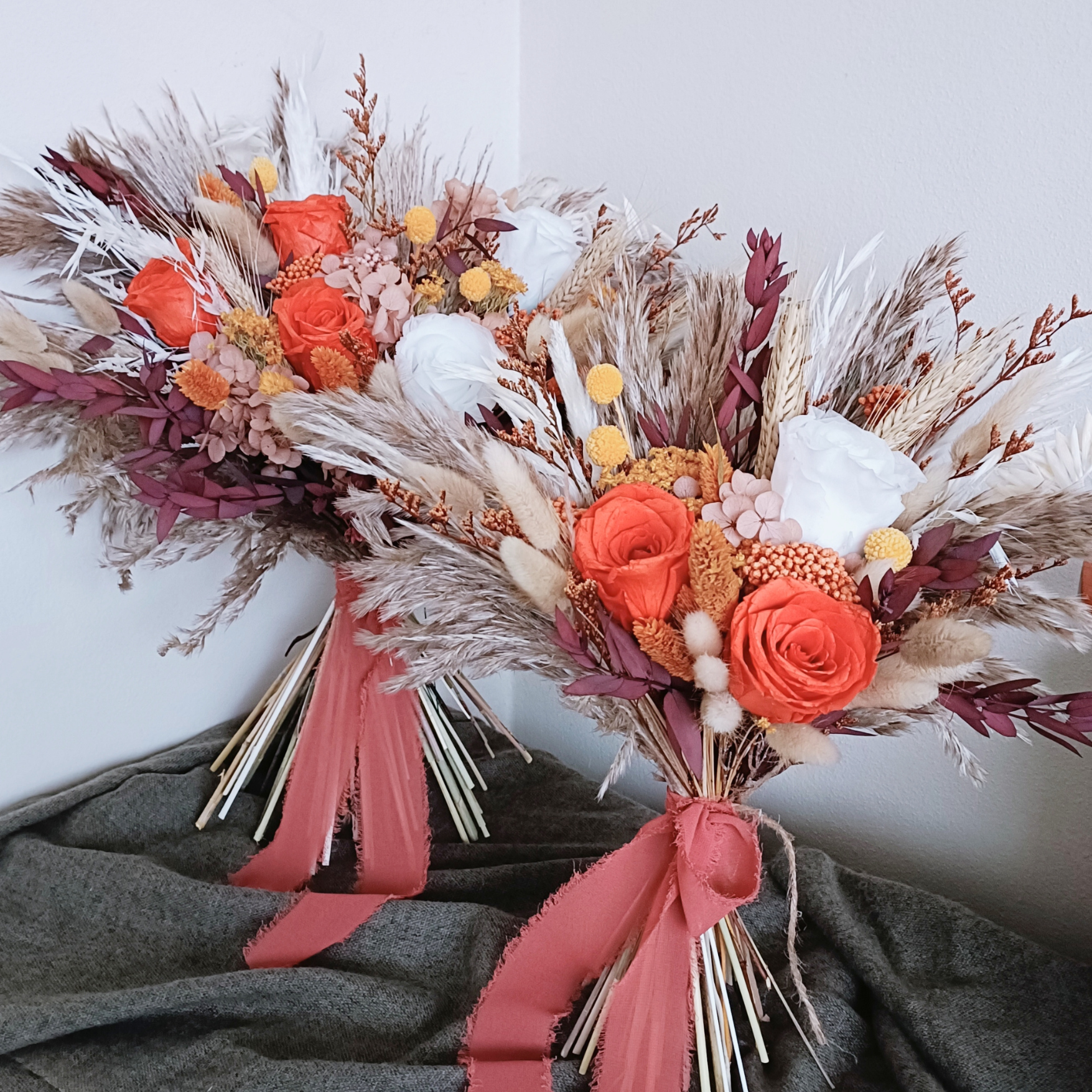 Wide dried bridal bouquet laid out on olive green fabric, showcasing preserved flowers in warm earthy tones â€“ orange, cream, plum, and beige with natural movement and boho style.