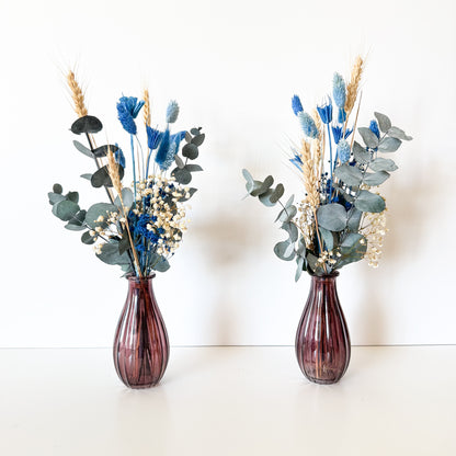 Two purple vases with floral arrangements on a white background