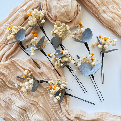 Set of decorative hair pins with floral elements on a beige fabric background