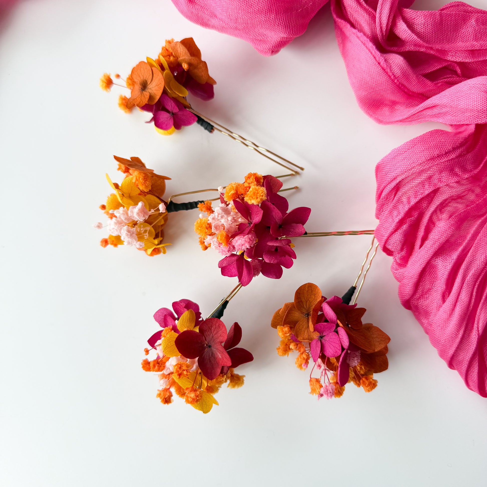 Colorful floral hair pins with pink fabric on a white background
