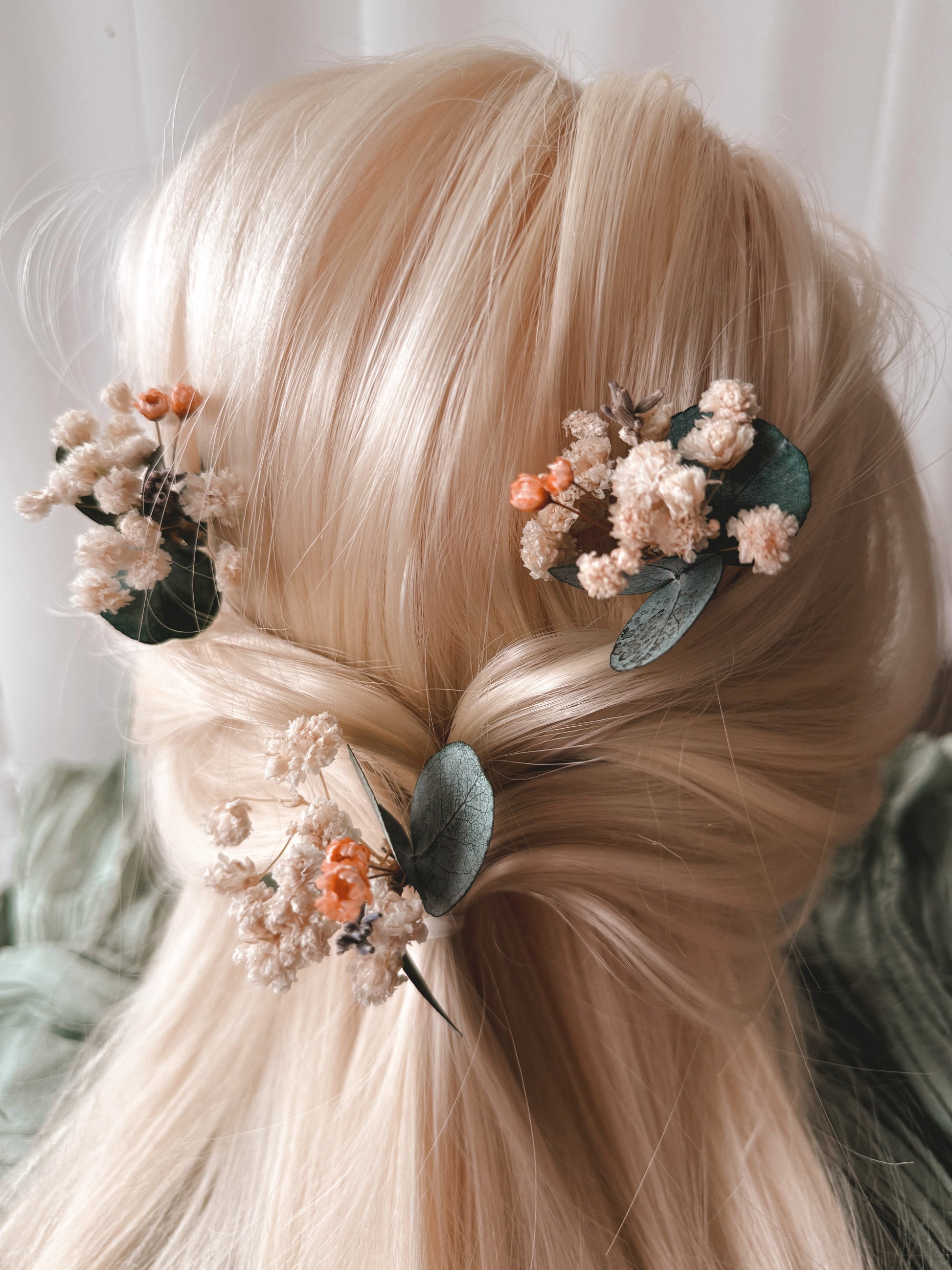 Blonde hair styled with floral hair accessories against a neutral background