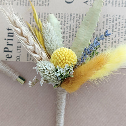  handcrafted boutonniÃ¨res featuring yellow billy buttons, fluffy bunny tails, dried lavender, and greenery â€“ styled on vintage newspaper background.