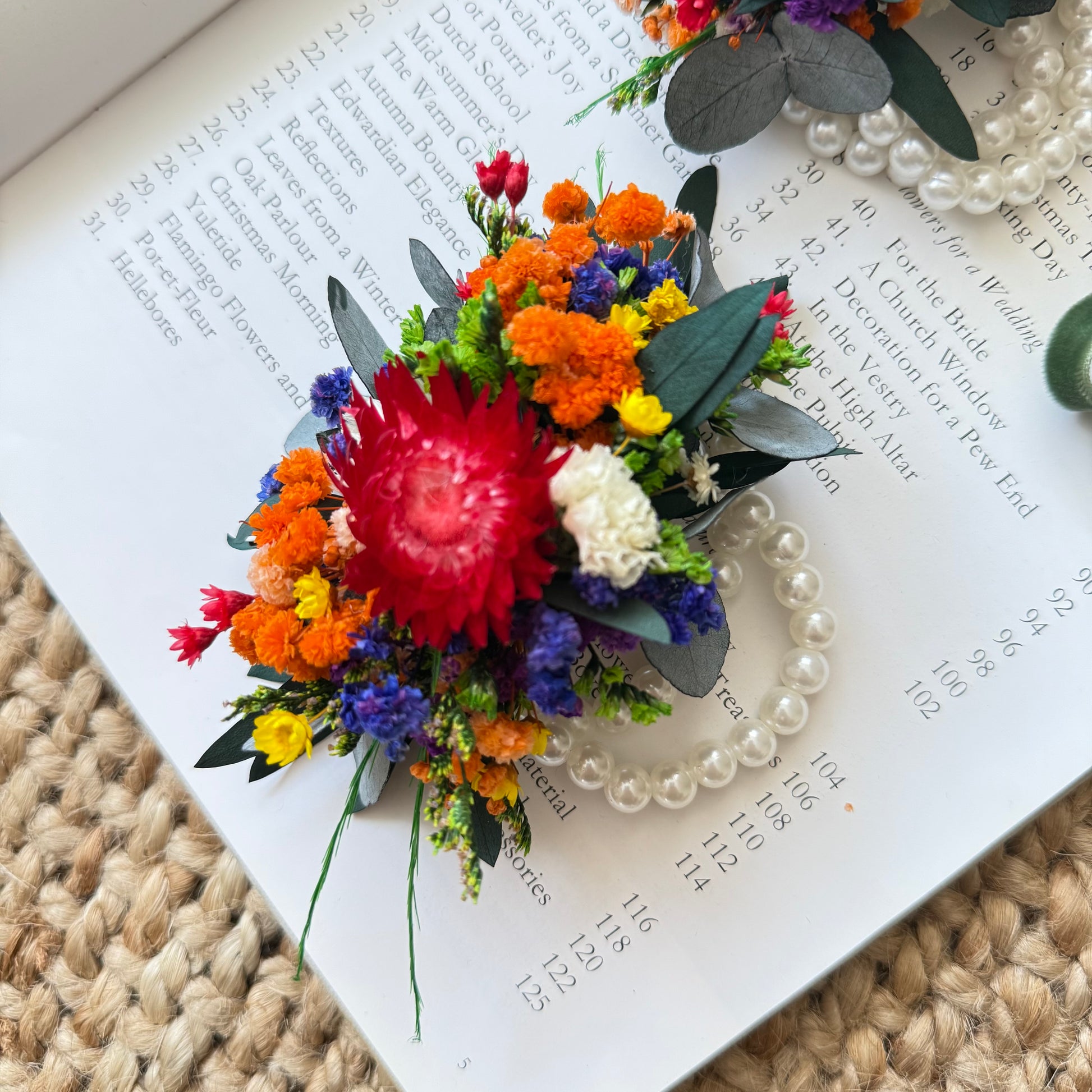 Handmade bridesmaid corsage with dried flowers in vivid wildflower tones, tied with green ribbon