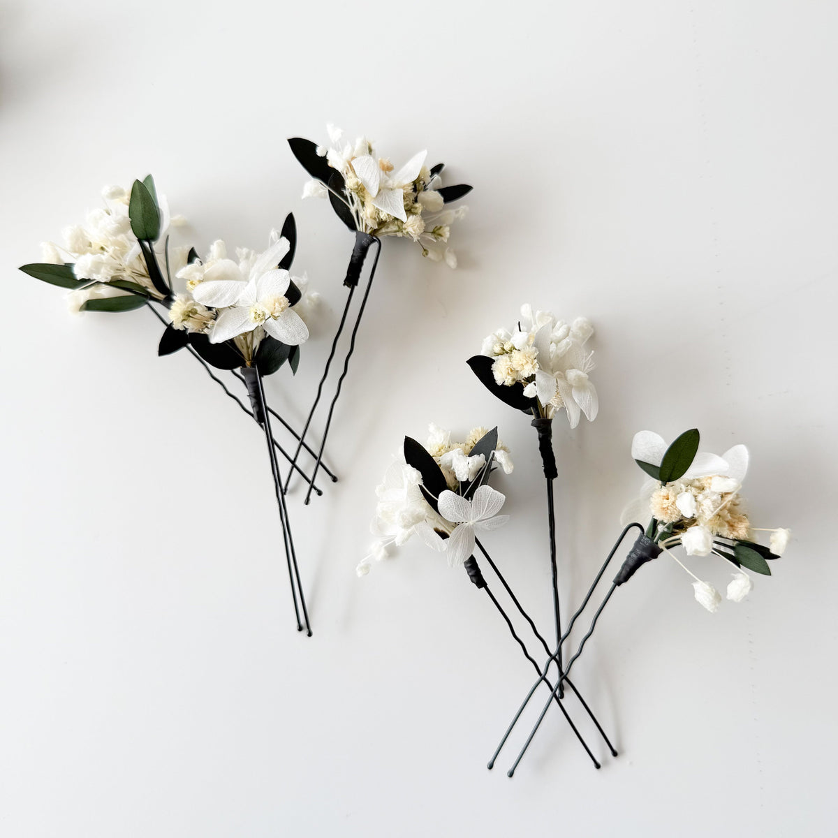 Close-up view of a floral hair pins with textured green eucalyptus leaves and delicate white dried flowers
