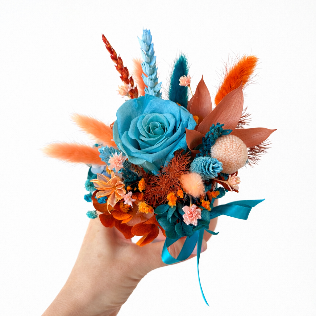 Hand holding preserved rose flower arrangement with turquoise and orange dried flowers
