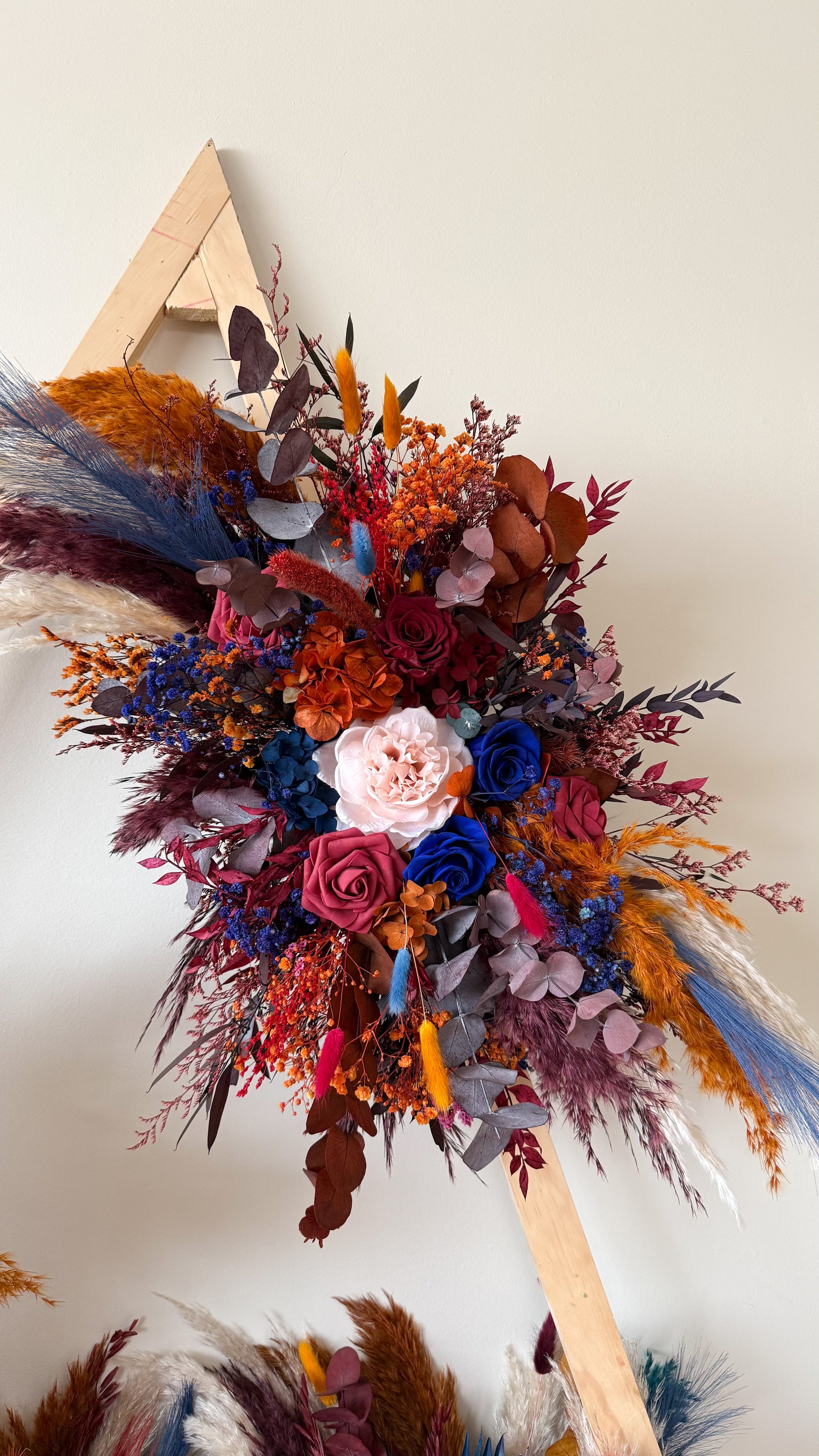 Dried wedding arch flowers in moody burgundy, terracotta and navy blue tone