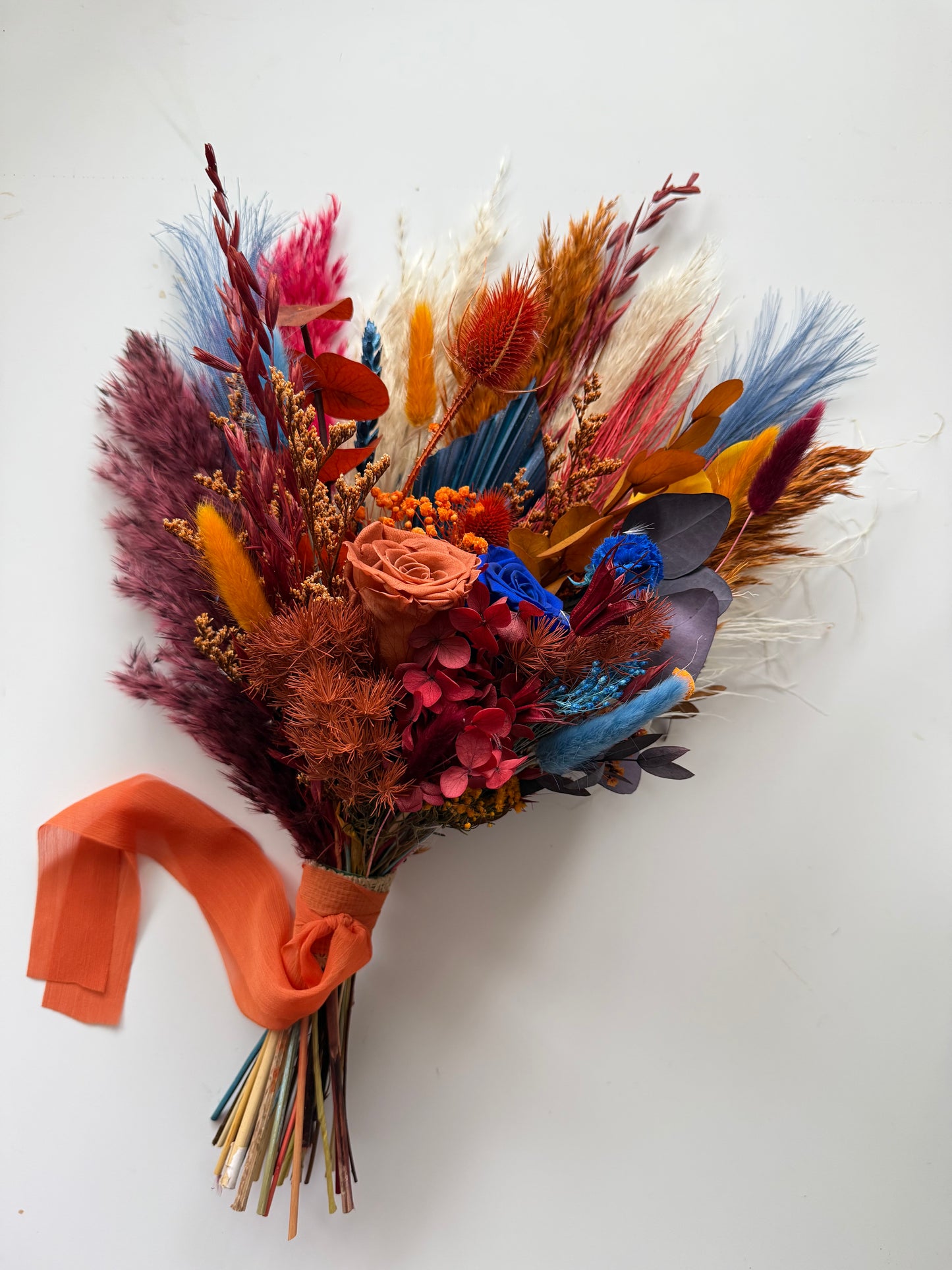 Bridesmaid bouquet in burgundy, rust orange and navy blue dried flowers.