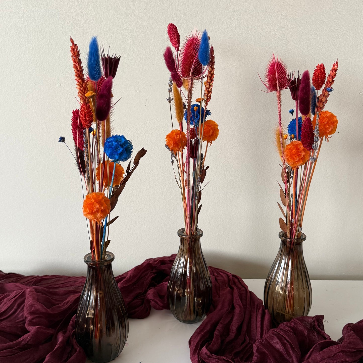 Matching dried wedding bud vase arrangements in burgundy and terracotta colours.