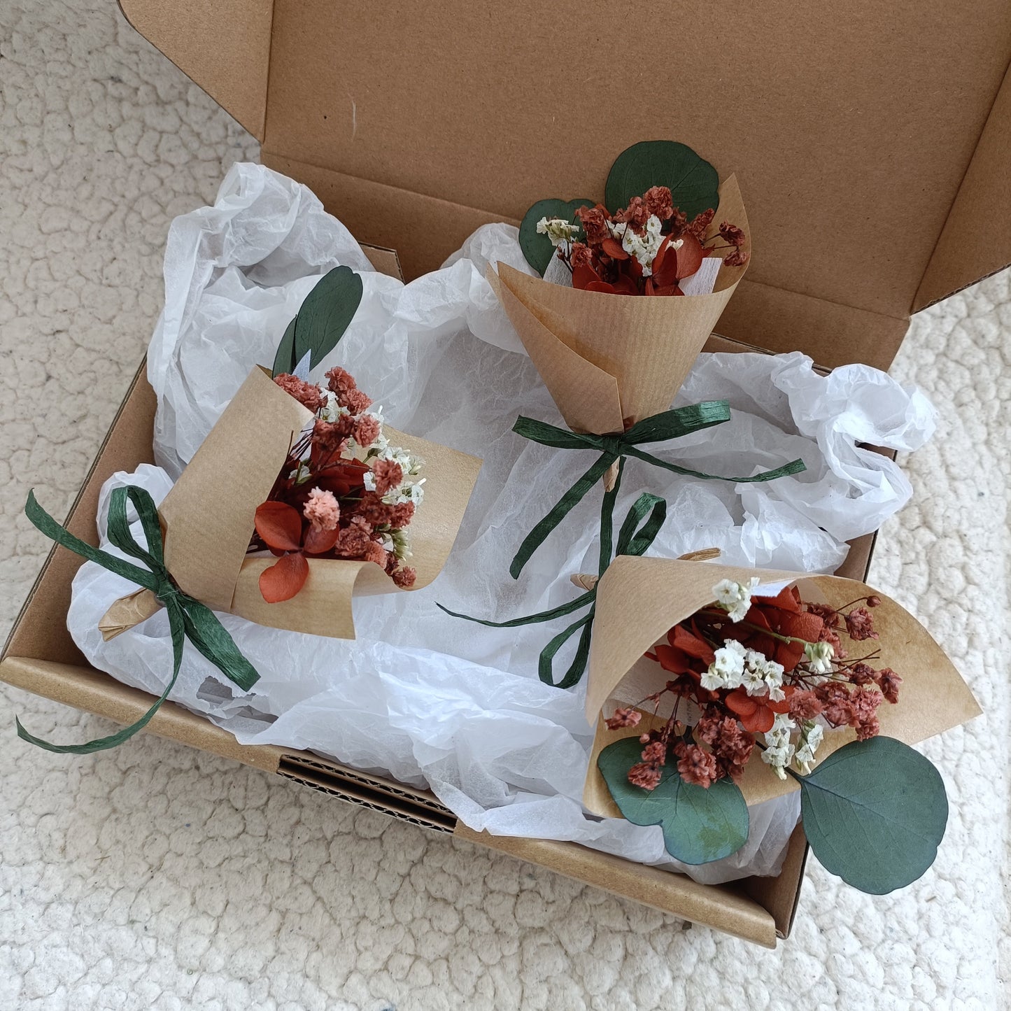 Set of two mini dried flower bouquets in a box, decorated with eucalyptus stems and green ribbon. Each bouquet is crafted with terracotta strawflowers, babyâ€™s breath, and wrapped in kraft paper. Perfectly packaged for wedding favours, thank-you gifts, or bridesmaid proposals with a natural and sustainable touch.