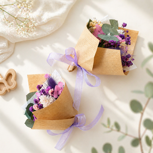 Two small paper-wrapped bouquets with purple ribbons on a light background