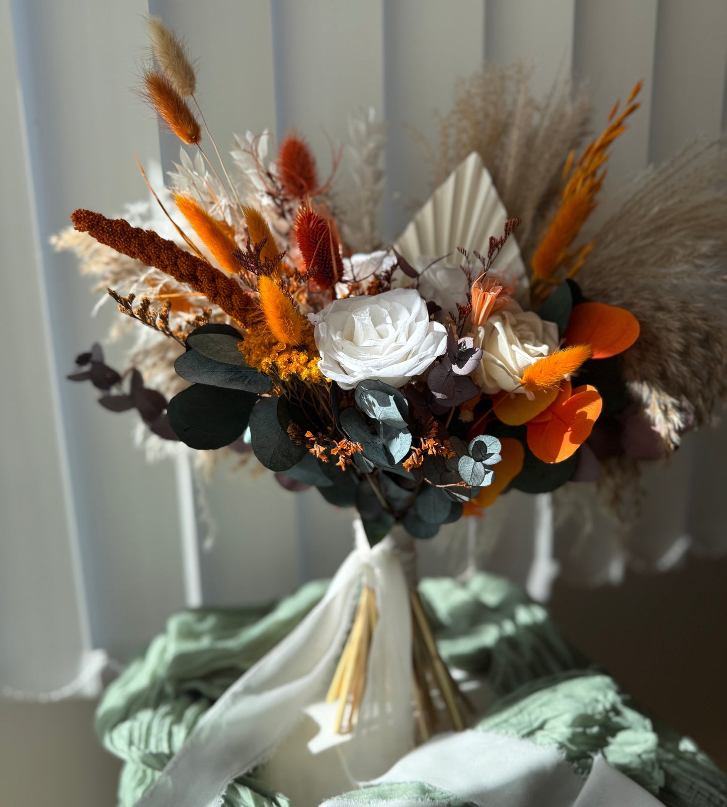 Bouquet of dried flowers with white, orange, and black elements on a neutral background